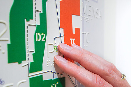 Finger tasten einen barrierefreien, taktilen Lageplan