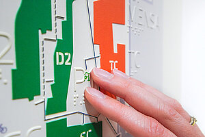 Finger tasten einen barrierefreien, taktilen Lageplan