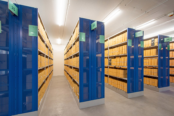 Archiv-Fachbodenregale mit blauen Vorsatzwänden sowie Regalbeschriftung