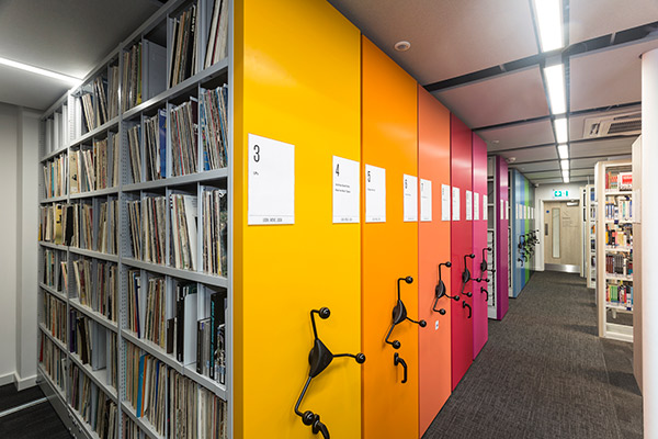 Verfahrbare Regalanlage in einer Bibliothek - die Vorsatzwände sind regenbogenfarben