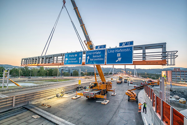 Montage einer Schilderbrücke vor der Voestbrücke im Hintergrund