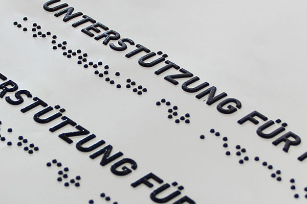 Taktile Normalschrift und Brailleschrift "Unterstütung für ..."