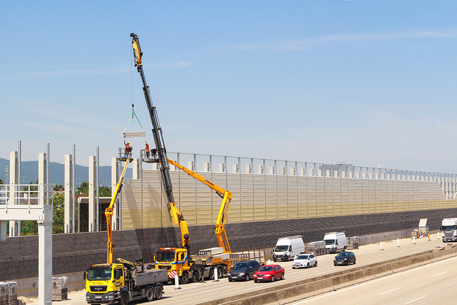 Monteue bei der Montage der hochabsorbierenden Lärmschutzelemente. Die Straße steht unter Verkehr